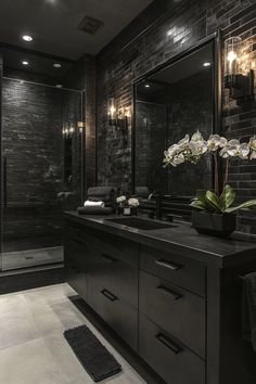 a bathroom with black tile walls and white flowers on the counter