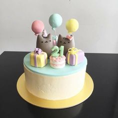 a birthday cake with two cats and balloons on the top is decorated in pastel colors