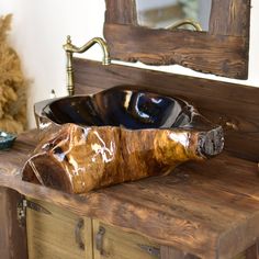 a wooden sink sitting on top of a wooden counter next to a mirror and vase