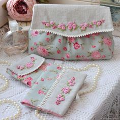 two purses with pink flowers on them sitting on top of a table next to pearls