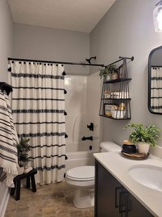 a bathroom with a shower curtain, toilet and sink in the corner next to a mirror