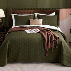 a bed with green bedspread and brown throw pillows