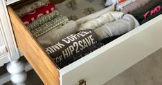 an open drawer filled with socks on top of a wooden table next to a white cabinet