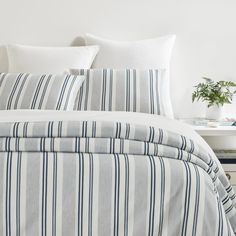 a bed with blue and white striped comforter next to a night stand on a table