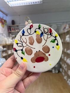 a hand holding a christmas ornament in the shape of a bear's paw