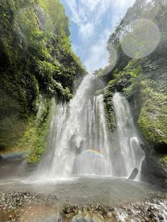 there is a waterfall with a rainbow in the middle and water running down it's side