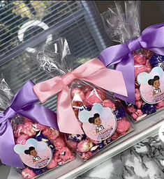 three bags of minnie mouse popcorn with purple bows on them, sitting in front of a window