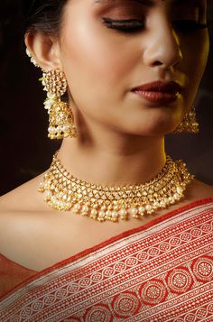 This captivating kundan set exudes both beauty and grandeur, featuring an intricate design that combines elegance with dramatic flair. Its striking 22K gold-plated mixed metal base is embellished with stunning kundan stones, creating a unique and eye-catching look. The set is complete with matching jhumkis that add a touch of opulence and sophistication. Ideal for special occasions, this set is sure to make a memorable statement, effortlessly blending tradition with contemporary glamour. Finish: Festive Kundan Temple Necklace Hand Set, Festive Hand Set Kundan Temple Necklace, Gold Meenakari Kundan Jewelry Sets, Gold Kundan Necklace With Cutdana For Reception, Elegant Gold Kundan Necklace With Cutdana, Gold Kundan Necklace With Stone Work, Gold Kundan Jewelry Sets With Cutdana, Gold Kundan Necklace For Festive Ceremonial Occasions, Gold Kundan Necklace With Stone Work For Reception