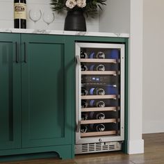 a wine cooler with several bottles and glasses in it next to a green cabinet on the floor