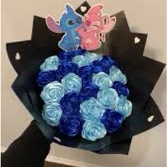 a bouquet of blue and pink roses on top of a black paper bag with cut outs in the shape of two ponies