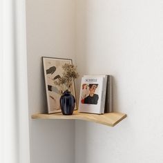 a shelf with two pictures and a vase on it