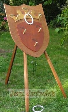 a wooden sign with a crown on it sitting in the grass next to a tree