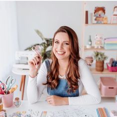 a woman sitting at a table with some crafting supplies on it's desk