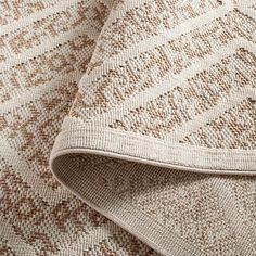 closeup of the textured fabric on an upholstered bedding set in beige and brown tones