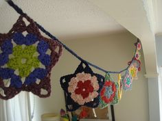 multicolored crocheted granny afghans hanging from the ceiling in a kitchen