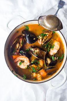 a pot filled with seafood and mussels next to a spoon