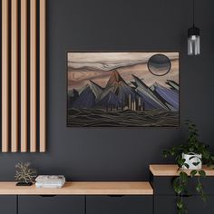 a painting hanging on the wall next to a wooden table with books and plant in it