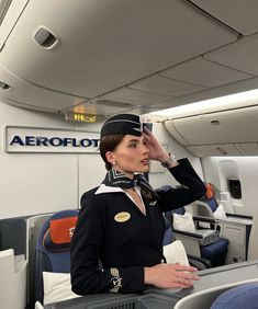 a woman in an airplane cabin saluting