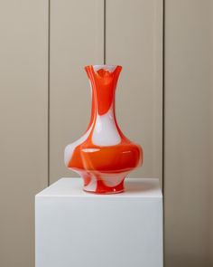 an orange and white vase sitting on top of a box