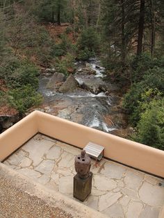 there is a small statue on the ledge next to a water fall in the woods