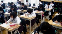 there are many students sitting at desks writing