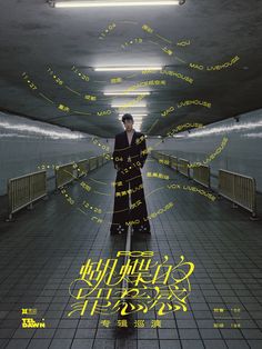 a man in a long black coat is standing on a walkway with yellow writing all over it