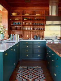 a kitchen with blue cabinets and white counter tops is pictured in this image, the rug has been placed on the floor