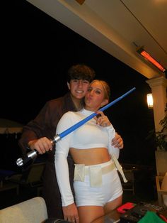 a man and woman dressed up as star wars characters posing for the camera with lightsabens