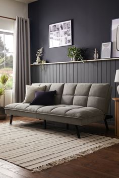 a living room with a gray couch and wooden flooring next to a large window