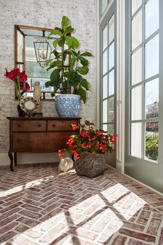 a room with a dresser, mirror and potted plants on the floor in front of it