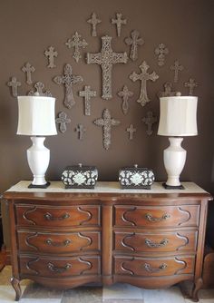 two lamps are sitting on top of a dresser in front of a wall with crosses