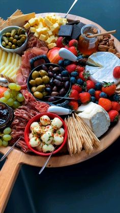 a wooden platter filled with different types of cheeses and meats on skewers