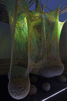 three large sculptures are lit up with green lights and balls in front of the sculpture