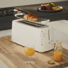 a toaster sitting on top of a cutting board next to two glasses of orange juice