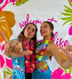 two young women in colorful clothing posing for the camera with their hands up and pointing