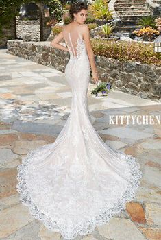 a woman in a white wedding dress standing on a stone walkway with her back to the camera