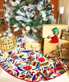 a christmas tree with presents under it in front of a brightly colored carpeted area rug