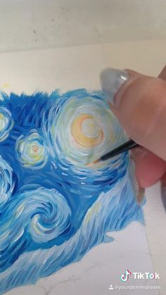 someone is painting the starry night with watercolors on white paper and using a brush