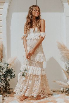 a woman standing in front of a white wall wearing a dress with ruffles