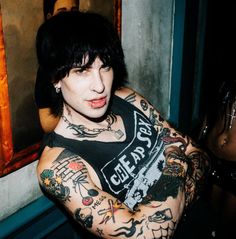 a man with black hair and tattoos on his arm