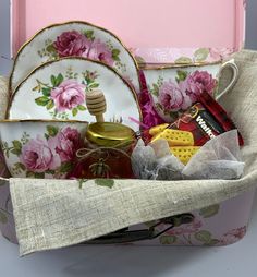 a basket filled with assorted items sitting on top of a pink tablecloth covered box