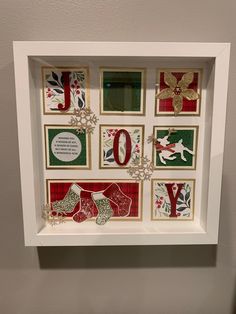 a white frame with christmas cards in it and the word joy is displayed on top