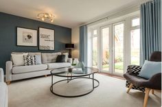 a living room filled with furniture and large windows covered in blue drapes, two chairs and a coffee table