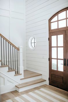 a door and some stairs in a room with white walls, wood floors and wooden doors