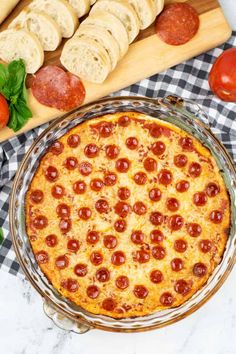 a pepperoni pizza sitting on top of a table next to sliced bread and tomatoes