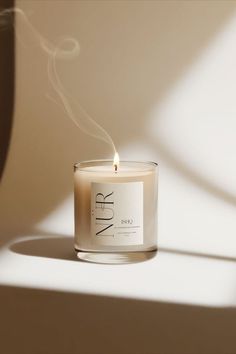 a candle that is sitting next to a wall with the word n r on it