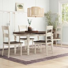 a dining room table and chairs with a rug on the floor in front of it