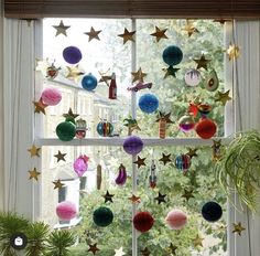 a window with christmas decorations hanging from it's sides and stars on the windowsill