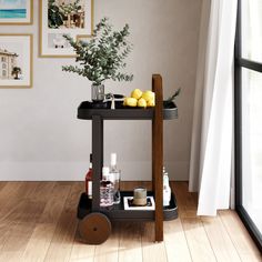 a black cart with lemons and bottles on it in front of a white wall