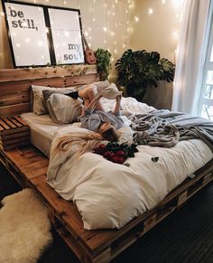 a person laying on top of a bed in a room with lights and plants behind it